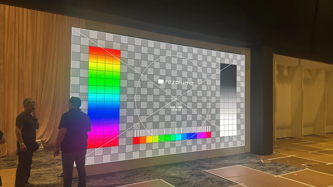 Large LED wall showing a test pattern while technicians check it